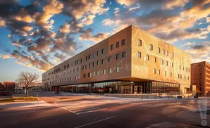 Modern building with patterned facade and glass ground floor, bathed in warm sunset light.
