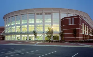 Modern round building with large windows and brick accents, at dusk.