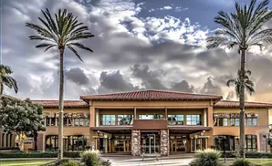 A building with palm trees and a cloudy sky.