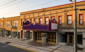 Marquee of a historic yellow brick theater with red-trimmed windows and purple accents.