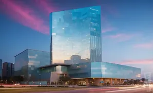 Modern glass skyscraper at dusk with colorful sky and car light trails.