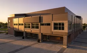Modern brick and wood-paneled building with large windows at sunset.
