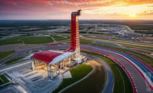 Aerial view of Circuit of the Americas racetrack and its iconic observation tower at sunset.