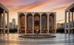 Metropolitan Opera House in Lincoln Center, NYC, at sunset with a fountain in the foreground.