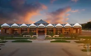 Modern building with peaked roof sections under a colorful sunset sky.