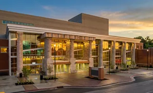 Exterior view of a modern brick and glass building with stone pillars at sunset.