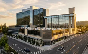 Modern hotel with glass facade and stone accents at sunset.
