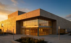 Modern building with textured concrete walls and large glass windows at sunset.
