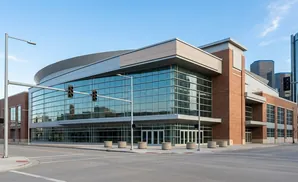 Modern convention center with a glass facade and brick accents, under a clear blue sky.