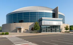 Modern circular building with a domed roof and large glass windows, seen from across a street with a crosswalk.