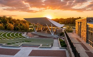 Outdoor amphitheater with tiered seating and a covered stage at sunset.