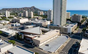 Aerial view of a city with tall buildings, a mountain, and the ocean in the background.