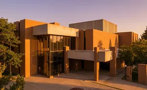 Modern brick building with large windows, illuminated by warm sunlight.