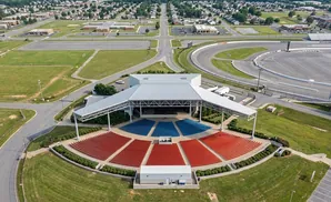Aerial view of an outdoor amphitheater with a stage and red and blue tiered seating.