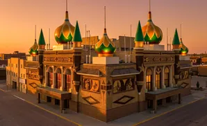 A uniquely decorated building with colorful domes and corn-cob mosaics, lit by warm sunset light.