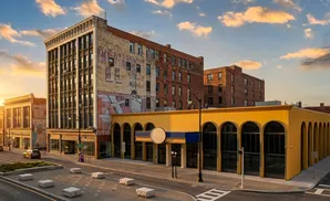 Sunset illuminates a street with historic buildings and arched storefronts.