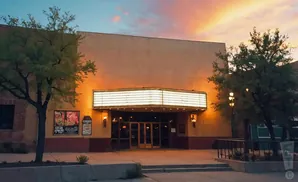 Exterior of a theater at dusk, with a marquee and trees.