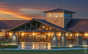 Large building with stone accents and a wooden covered entrance at sunset with a dramatic orange sky.