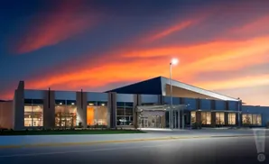 Modern building with large windows and a dramatic sunset sky.