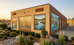 Building with murals of a river, a person in a canoe, and a scenic landscape.