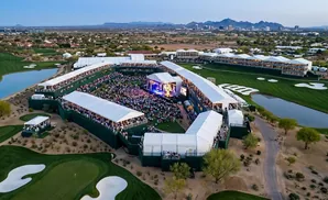 Aerial view of a golf tournament with a large concert stage and spectator seating area.