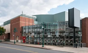 A modern brick and glass building with a large blank billboard in front.