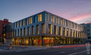 Modern multi-story building with large windows at dusk.