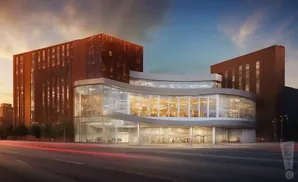 A modern building with a curved glass facade and brown brick wings at sunset.