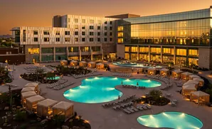 Resort with large illuminated pools and cabanas at dusk.