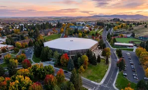 Aerial view of a university campus with colorful fall foliage, an arena, and a baseball field at sunset.