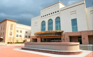 Modern building with arched windows and brick accents, under a cloudy sky.