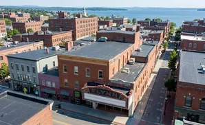 Aerial view of the Flynn theater and surrounding brick buildings in a waterfront town.