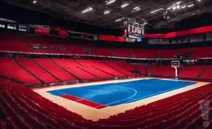 An empty basketball arena with bright red seats and a blue court.