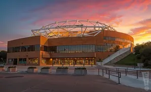 A large, modern building with a domed roof, at sunset.