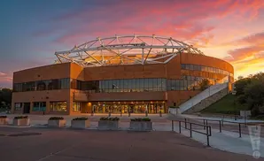 A modern, rounded building with a dome-like structure at sunset.