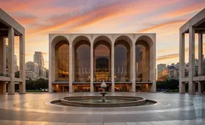 Lincoln Center's Metropolitan Opera House with arched windows and a fountain at sunset.