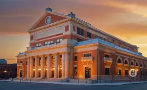 Grand brick building with classical columns and arched windows at sunset.