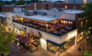 Rooftop restaurant with patrons dining and socializing at dusk.
