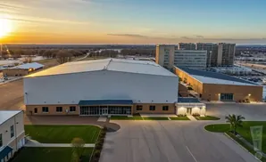 Aerial view of large warehouse-style buildings at sunset with high-rise buildings in the background.
