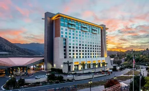 A hotel at sunset with mountains and a colorful sky.