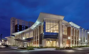 Modern building at dusk with curved facade, large windows, and brick accents.