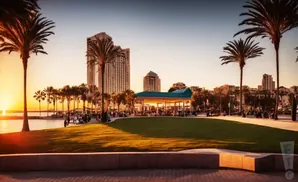 Sunset view of a waterfront park with palm trees, city skyline, and people enjoying the evening.