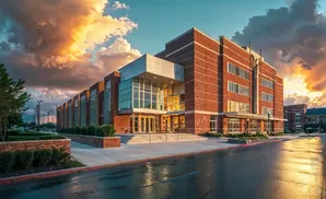 Modern brick building with glass entrance and dramatic sunset clouds.