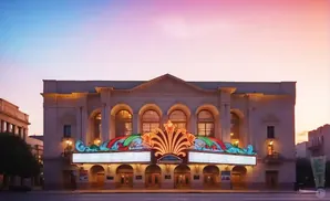 Art Deco theater at sunset with marquee lights and ornate facade.