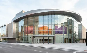 Modern building with curved glass facade featuring colorful art panels and glass doors.
