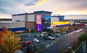 An aerial view of a modern casino with a colorful digital billboard and a parking lot filled with cars.