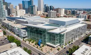 Aerial view of a large modern convention center with glass facades and a blue bear sculpture.