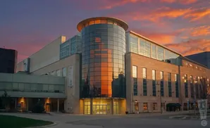 Modern building with a glass tower at sunset.