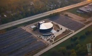 Aerial view of a modern church with a large, curved roof and extensive parking lots.