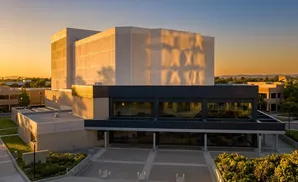 Modern building with large windows and textured walls bathed in golden sunset light.
